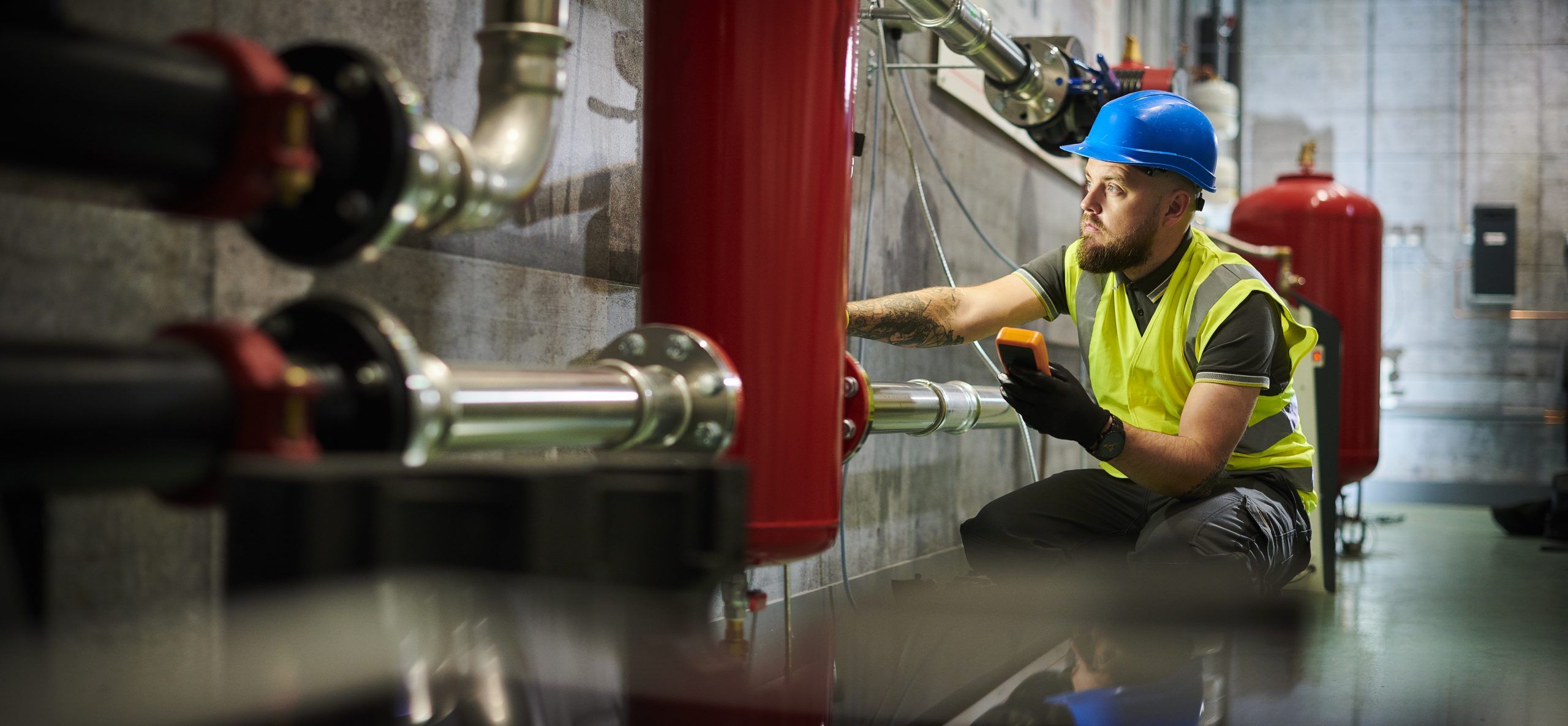 Monteur met helm werkt aan leidingen in een technische ruimte